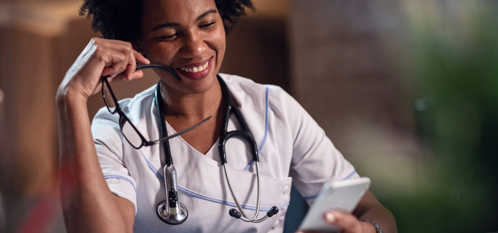 A smiling doctor reads a text message